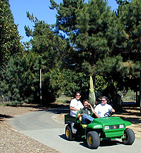 Leo, Chris, and Greg driving a small cart with bud in back